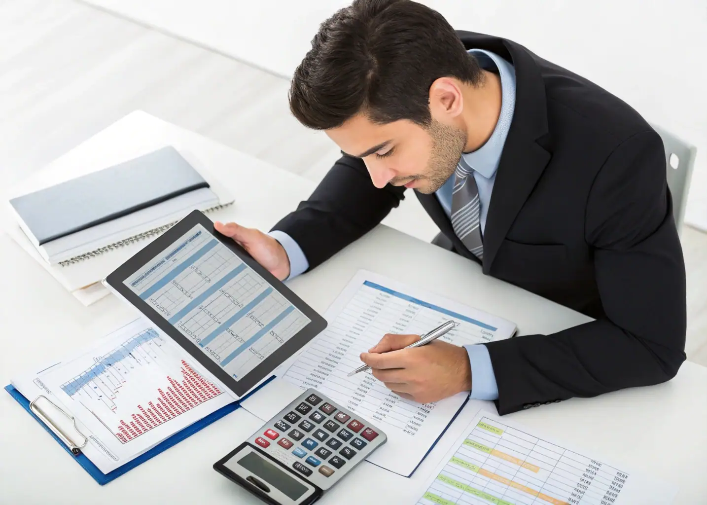 Análisis Financiero Estratégico para Emprendedores Emprendedor hispano analizando números financieros en tablet con documentos de presupuesto y calculadora