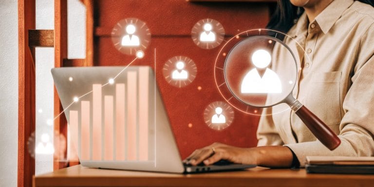 mprendedor usando una lupa para analizar un Buyer Persona, con iconos de datos flotando, simbolizando la investigación de cliente ideal.